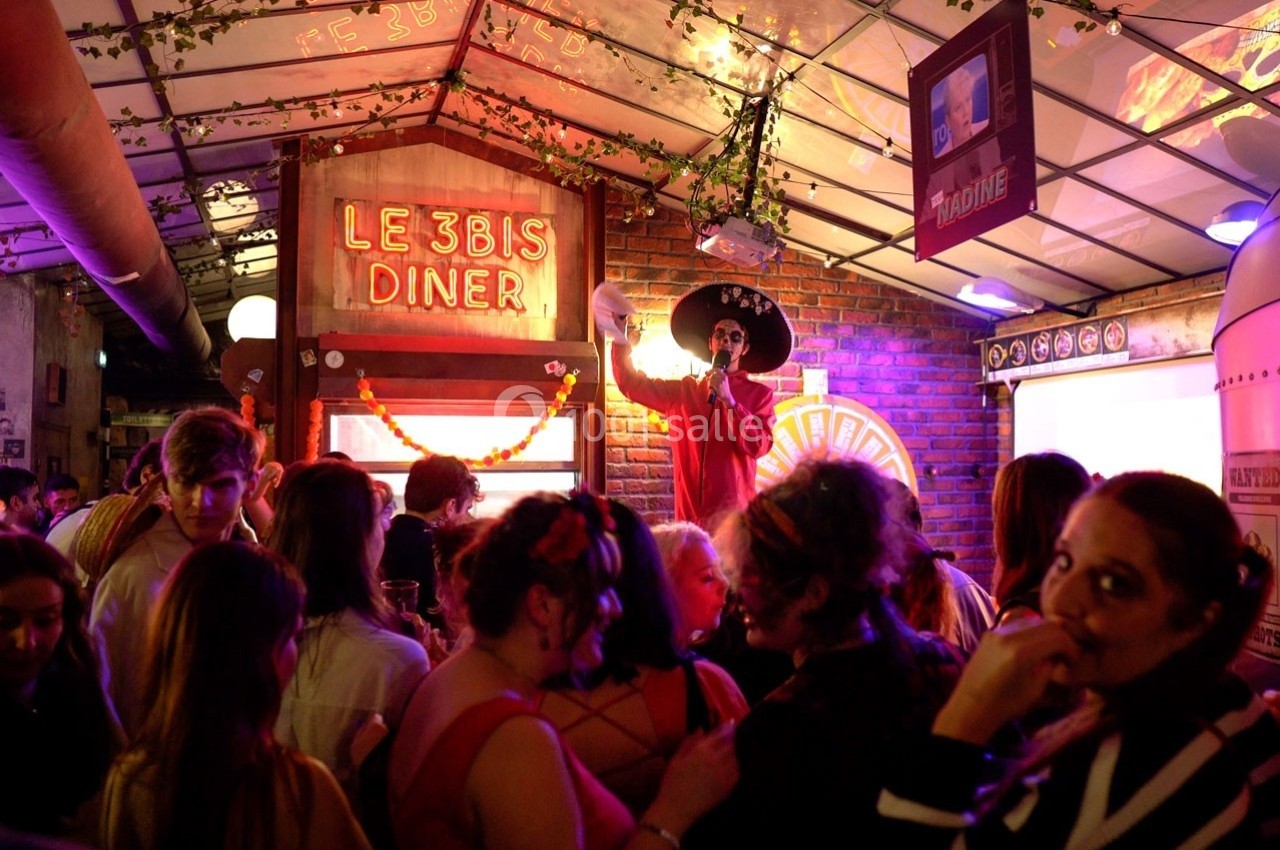 Un homme déguisé avec un sombrero anime une soirée festive dans un restaurant décoré de lumières et de guirlandes.