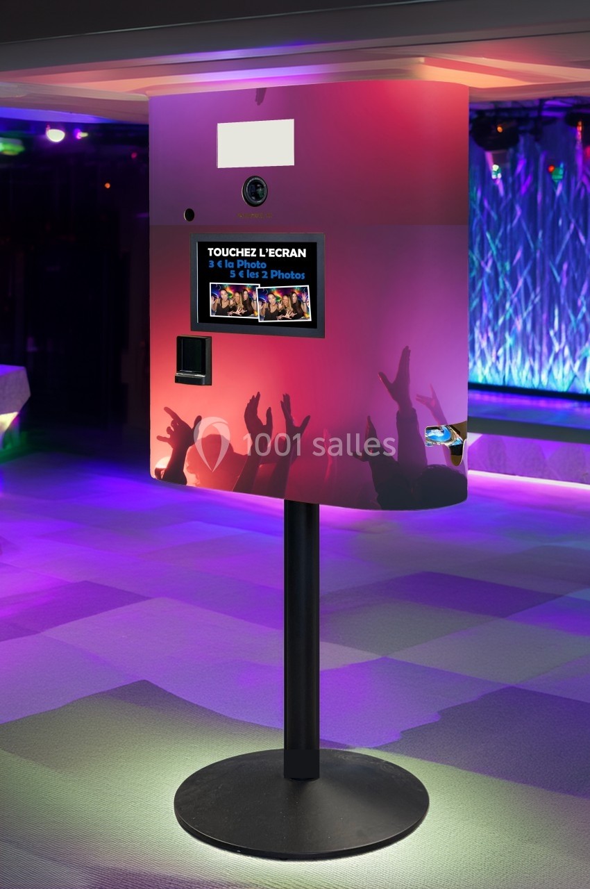 Borne photo interactive sur pied dans un environnement lumineux avec écran tactile et fente pour impression.