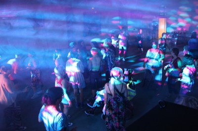 Miniature DJ Toulouse (Haute-Garonne) - Pmn Event #19 Personnes dansant et discutant lors d'une soirée en extérieur, éclairée par des lumières colorées et décorée de guirlandes.