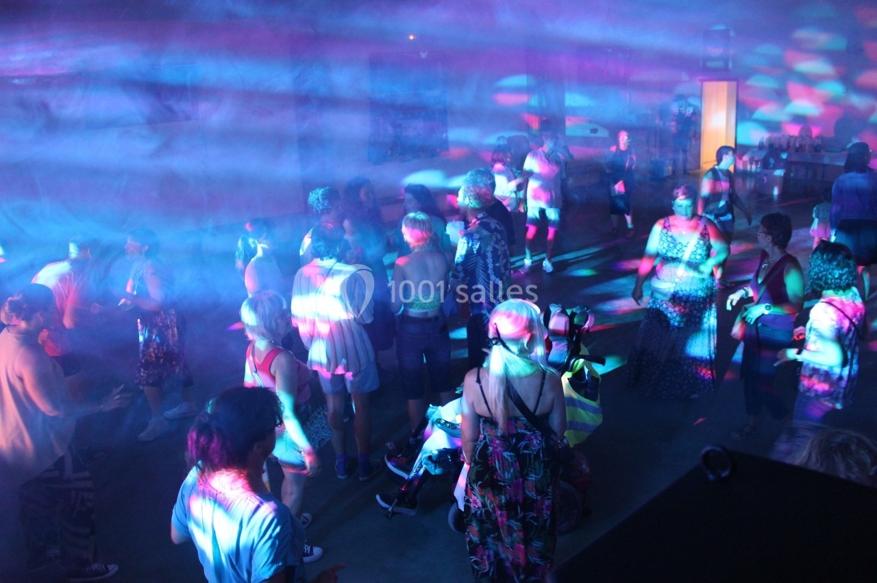 Groupe de personnes dans une salle éclairée par des lumières colorées, dans une ambiance festive.