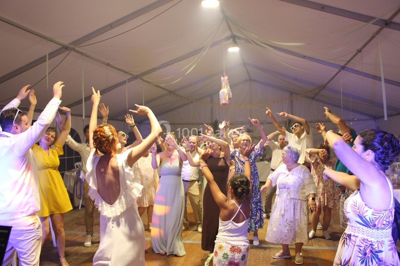 Groupe de personnes dansant sous une tente éclairée lors d'une fête ou d'un événement festif.
