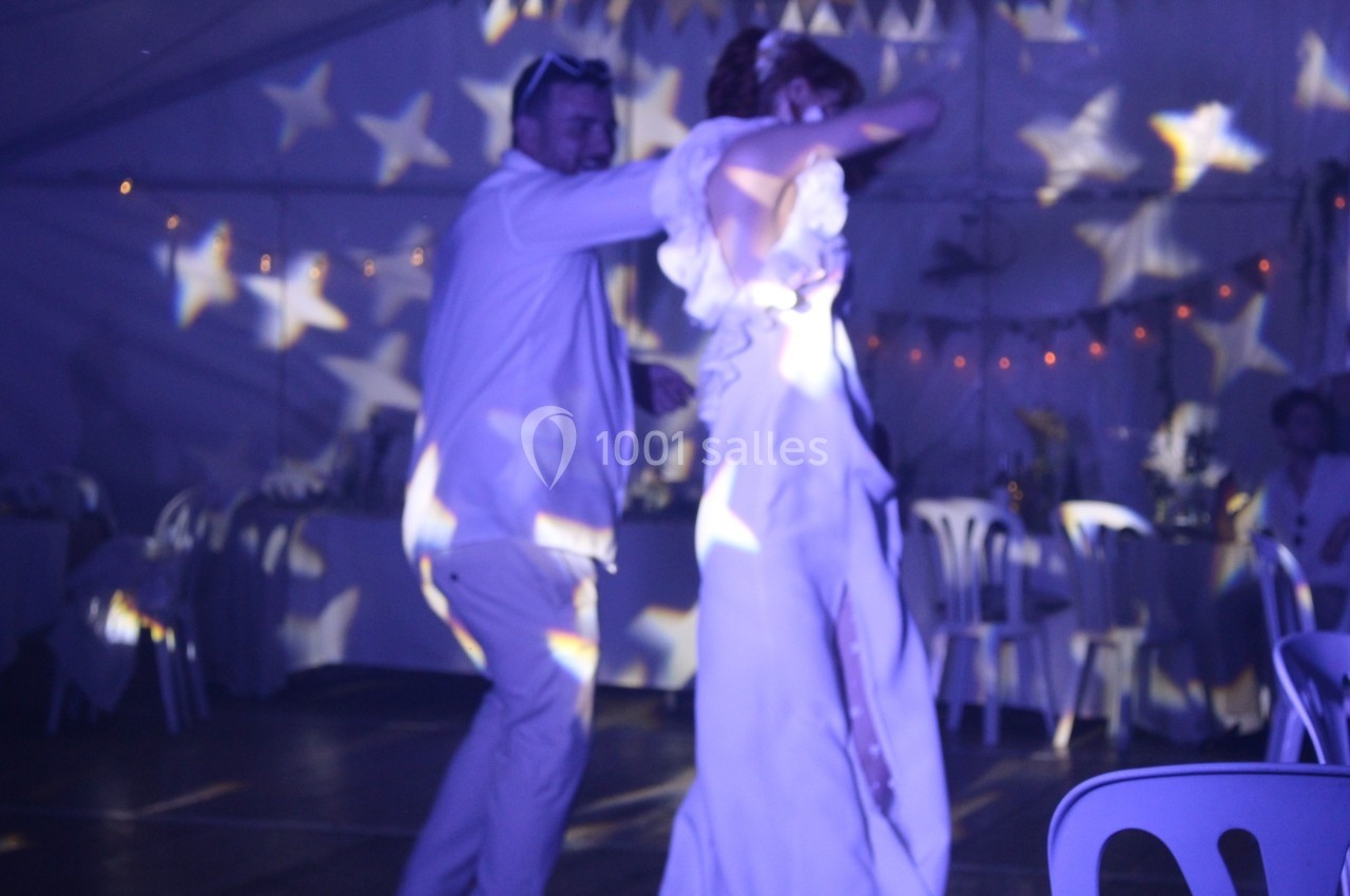 Un couple danse sous des lumières en forme d'étoiles dans une salle décorée pour un événement festif.