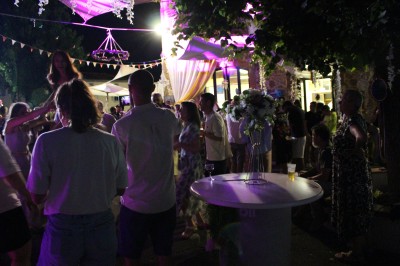 Miniature DJ Toulouse (Haute-Garonne) - Pmn Event #36 Personnes dansant et discutant lors d'une soirée en extérieur, éclairée par des lumières colorées et décorée de guirlandes.