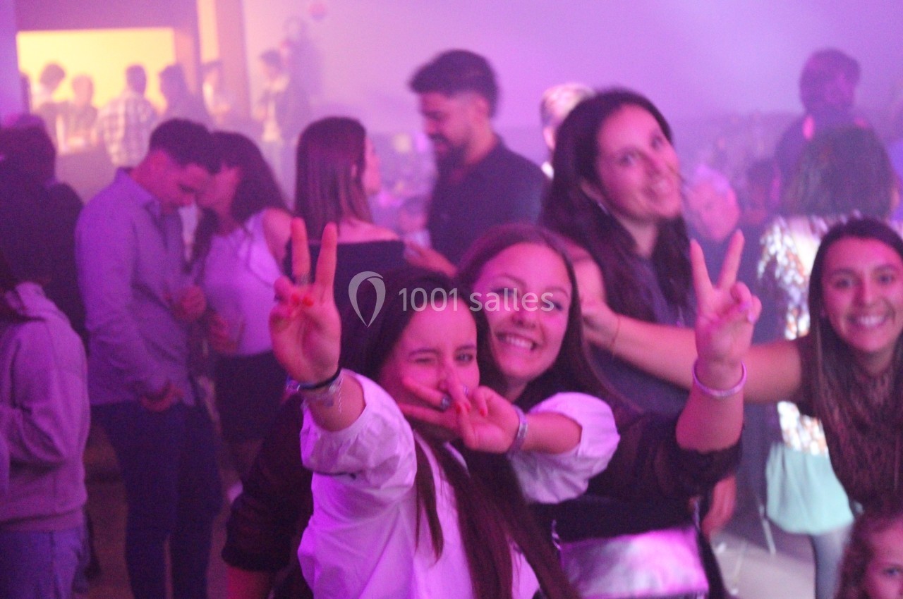 Des personnes souriantes posent et font des signes de paix dans une ambiance festive et lumineuse.