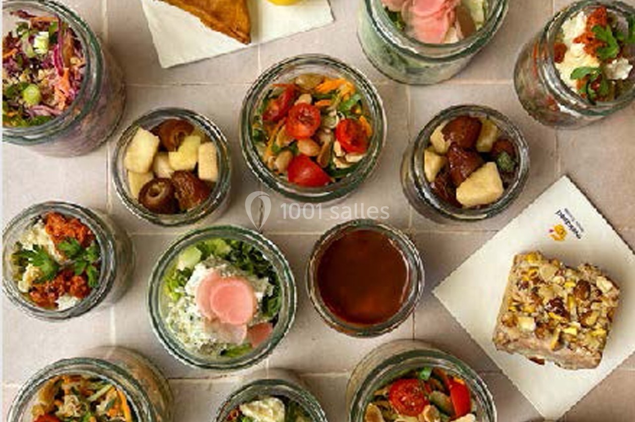 Vue de dessus de plusieurs bocaux contenant des plats variés, accompagnés de sauces et d'une part de gâteau.