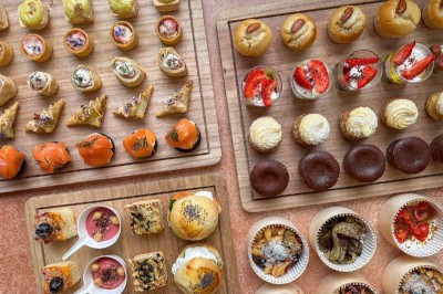 Plateaux en bois garnis de bouchées salées et sucrées variées, présentées pour un buffet ou un événement.