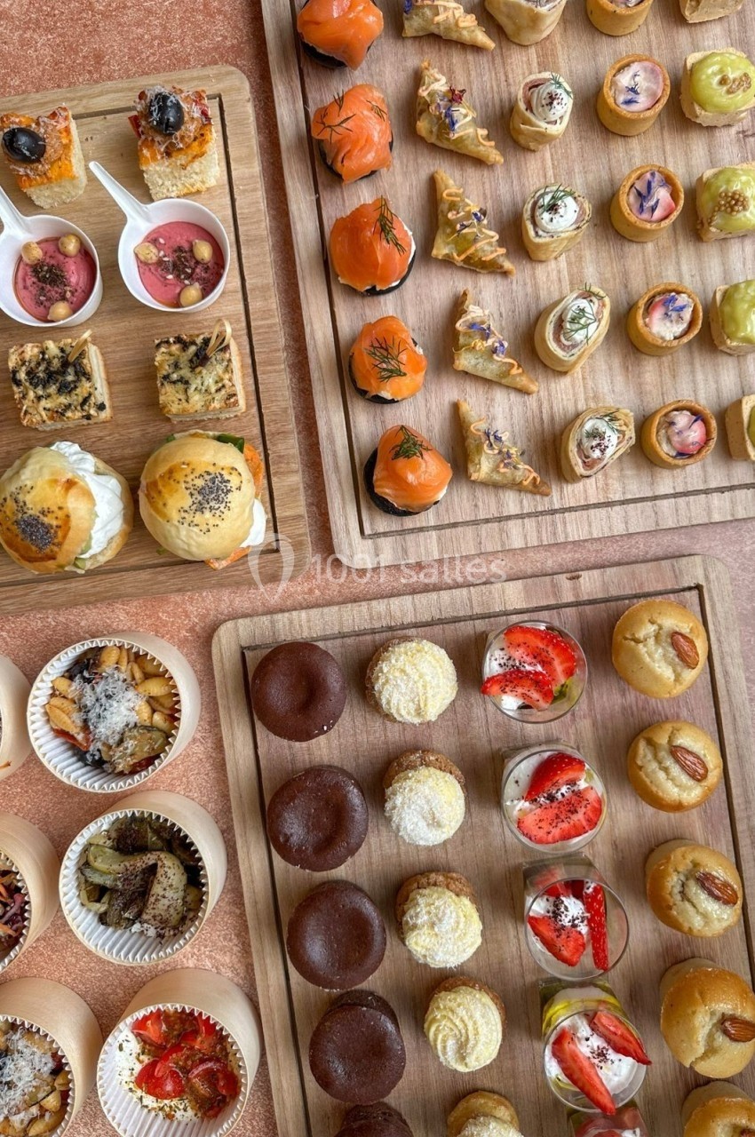 Plateaux en bois garnis de bouchées salées et sucrées variées, présentées pour un buffet ou un événement.