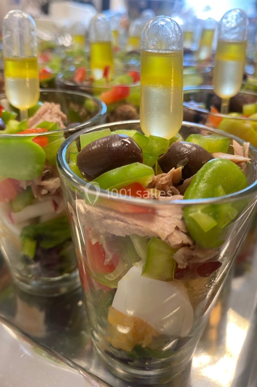 Verrines garnies de légumes, thon, olives et pipettes d'huile, présentées sur un plateau.
