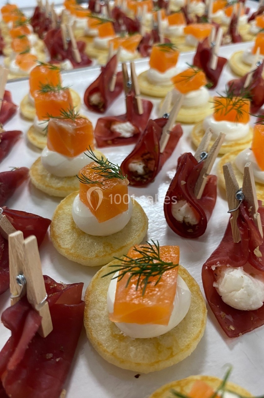 Assortiment de canapés avec saumon, crème et aneth sur blinis, et viande séchée garnie de fromage frais.
