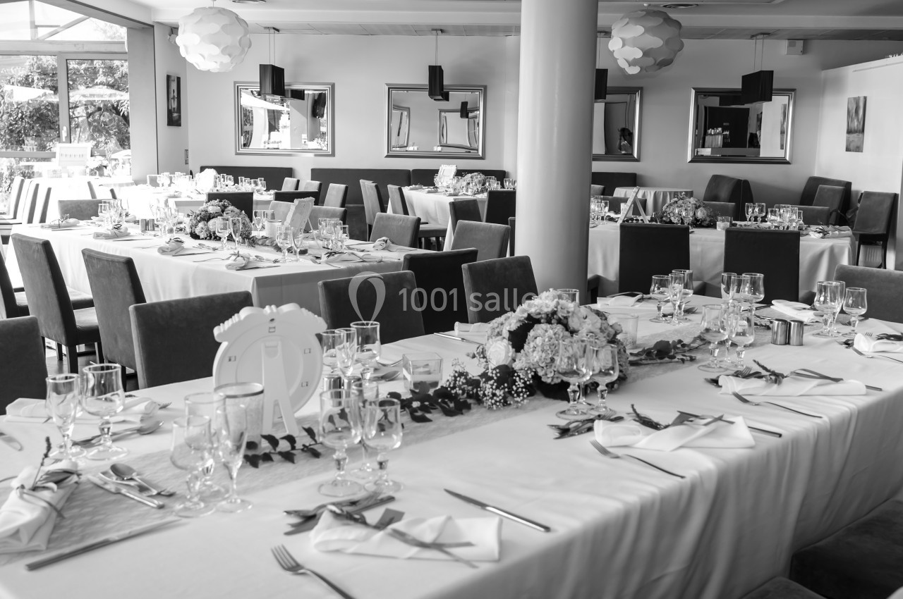 Salle de réception élégamment décorée avec des tables dressées pour un événement, vue en noir et blanc.