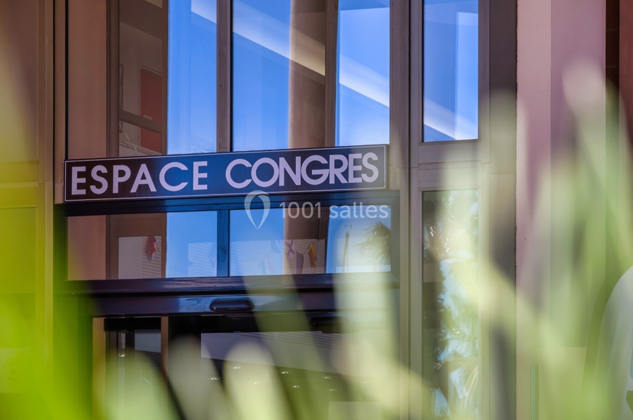 Façade vitrée avec une enseigne indiquant ’Espace Congrès’, entourée de végétation au premier plan.