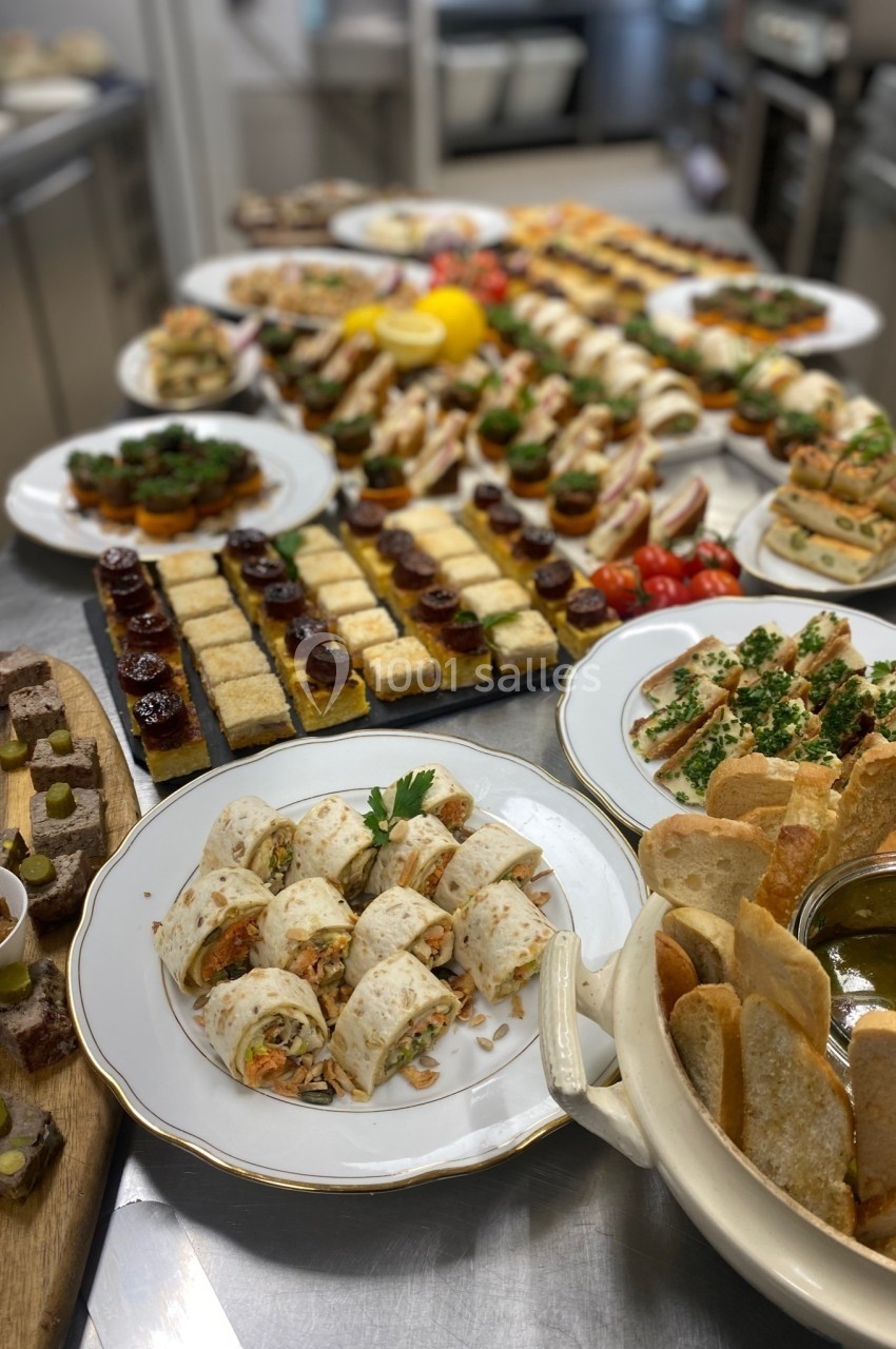 Assortiment de plats et amuse-bouches variés disposés sur une table dans une cuisine professionnelle.