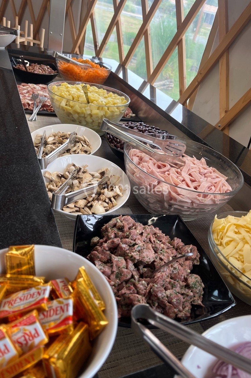 Buffet avec divers ingrédients frais, tels que charcuterie, légumes, fromages et bonbons, disposés dans des bols et…