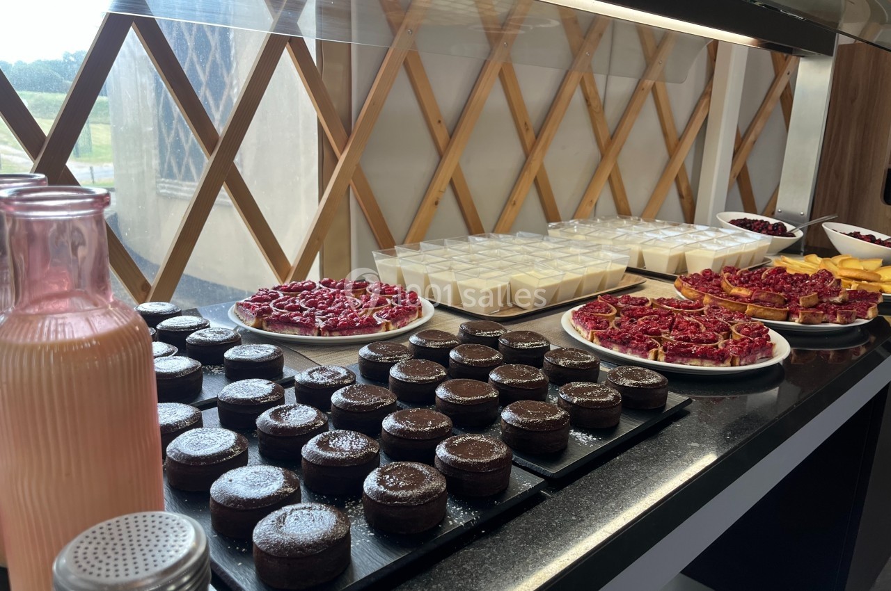 Buffet de desserts avec gâteaux au chocolat, verrines, fruits rouges et pichet de boisson rose sur un comptoir.