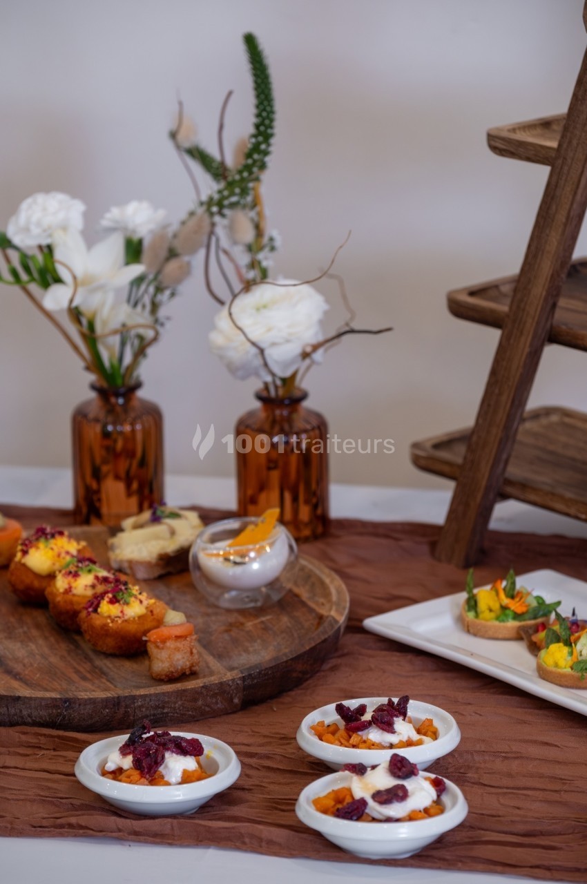 Assortiment de desserts et amuse-bouches disposés sur une table avec des fleurs en arrière-plan.