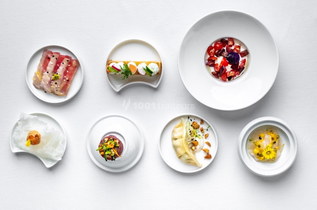 Assortiment de plats gastronomiques présentés dans des assiettes blanches sur une table blanche.