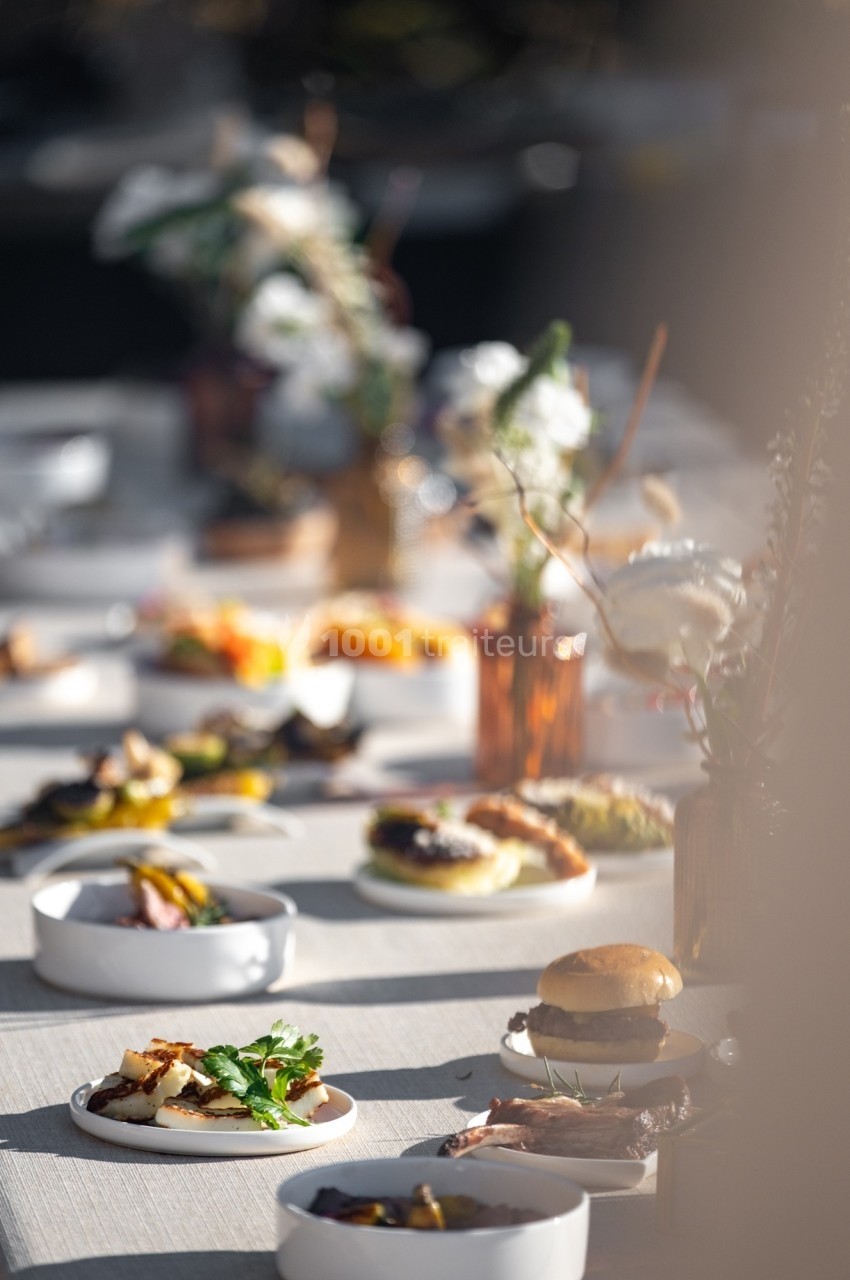 Table dressée avec divers plats et décorations florales, éclairée par une lumière naturelle douce.