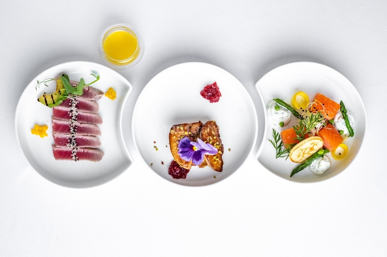 Trois assiettes de plats gastronomiques comprenant thon, foie gras et saumon, accompagnés de garnitures raffinées.