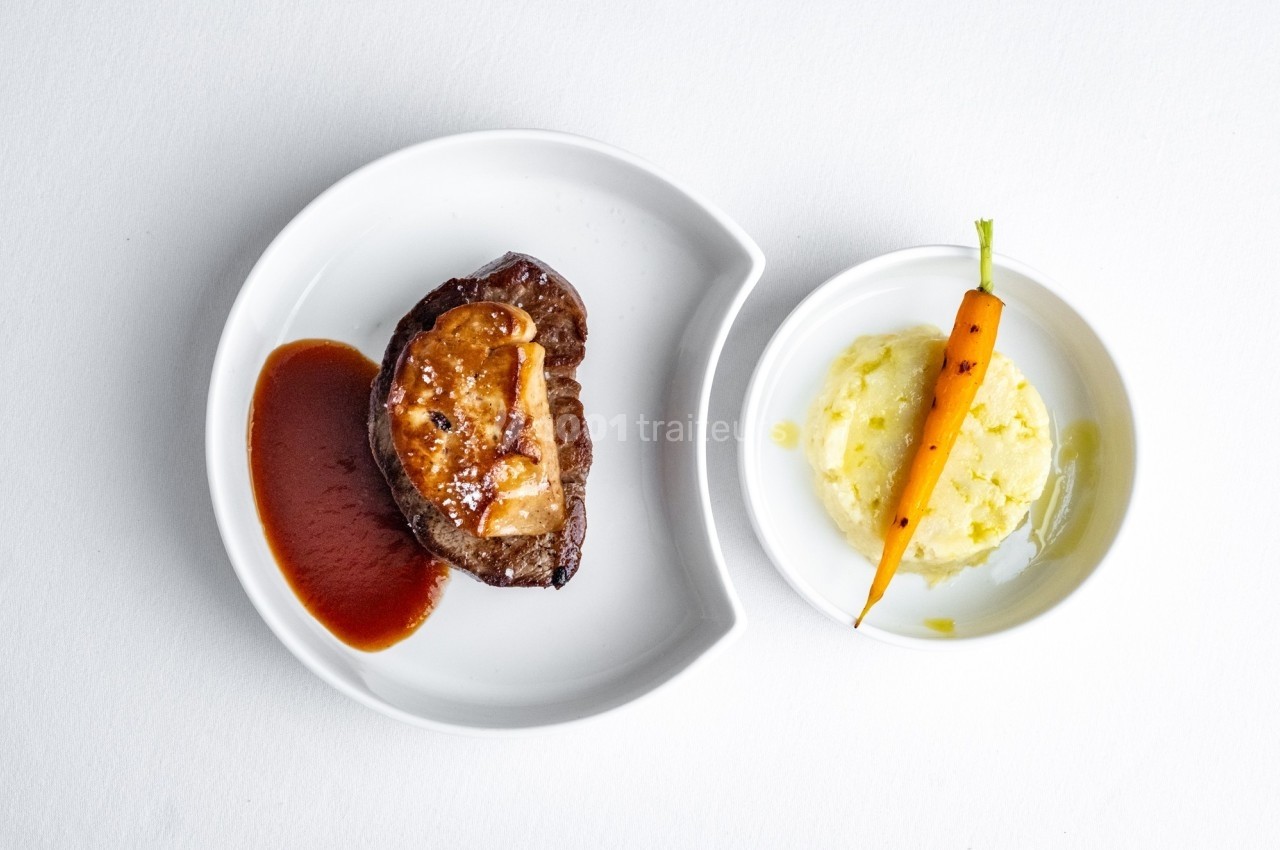 Assiette avec un filet de viande, sauce, purée de pommes de terre et une petite carotte entière.