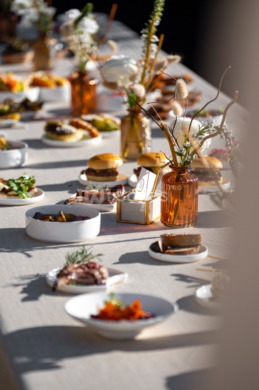 Table dressée avec divers plats, desserts et décorations florales dans des tons naturels et lumineux.