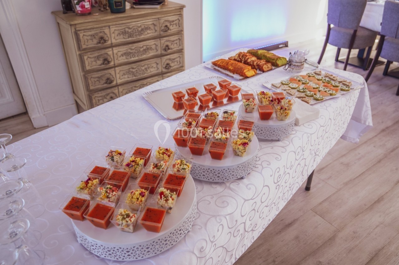 Buffet de verrines et amuse-bouches variés disposés sur une table recouverte d'une nappe blanche.