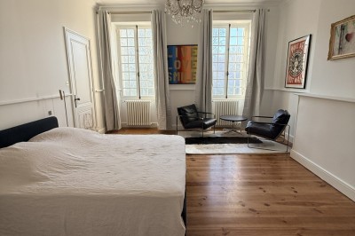 Pelouse verdoyante bordée d'arbres sous un ciel bleu clair, avec une haie en arrière-plan.