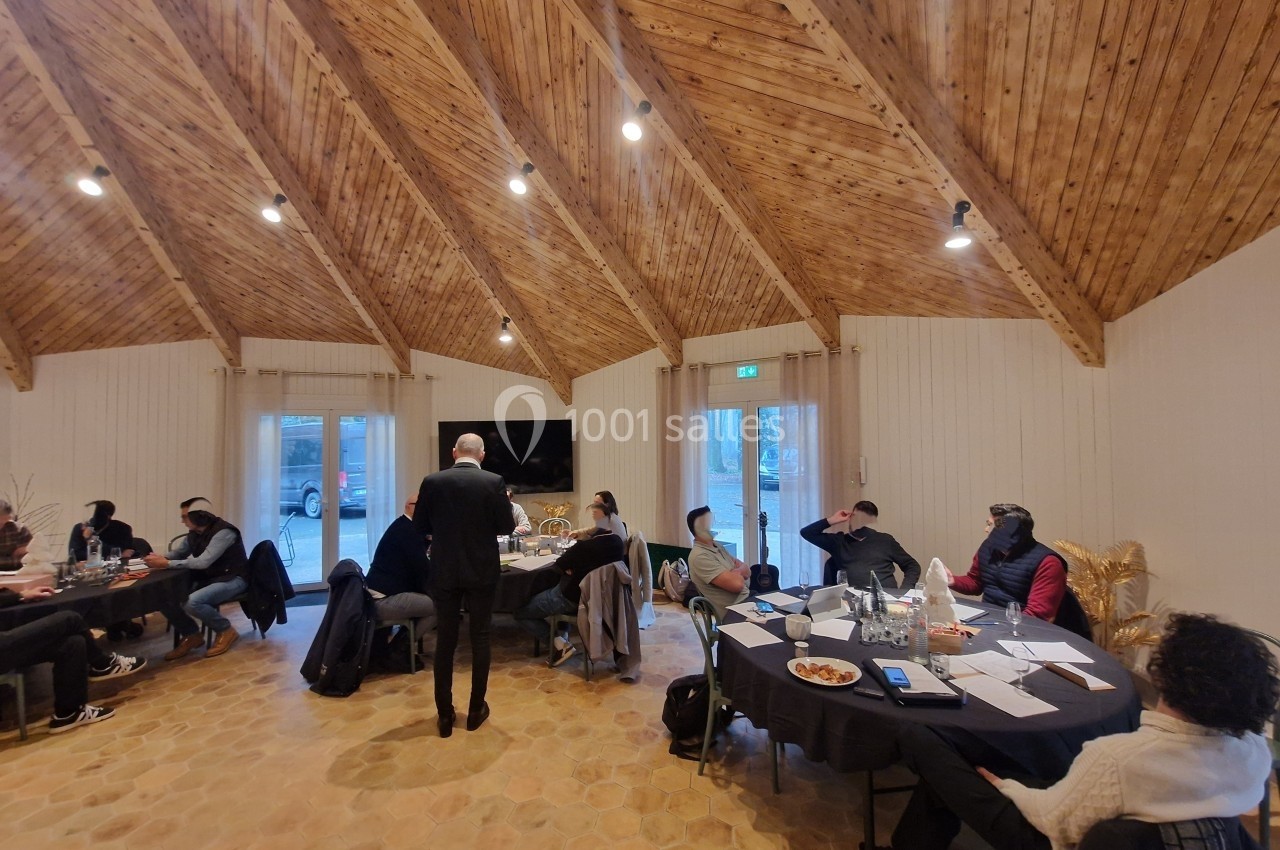 Personnes assises autour de tables dans une salle avec plafond en bois, participant à une réunion ou un atelier.