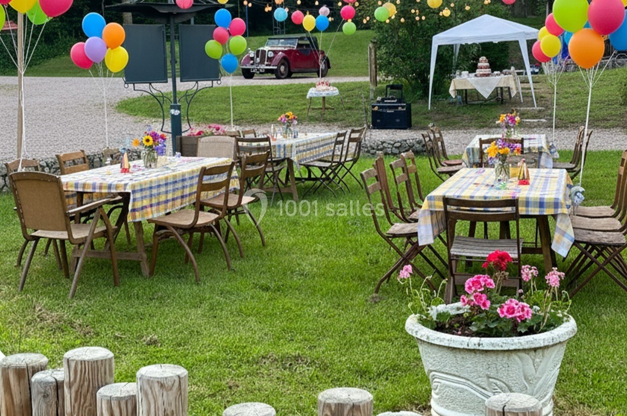 Tables décorées avec nappes à carreaux, ballons colorés et fleurs, disposées en extérieur pour un événement festif.