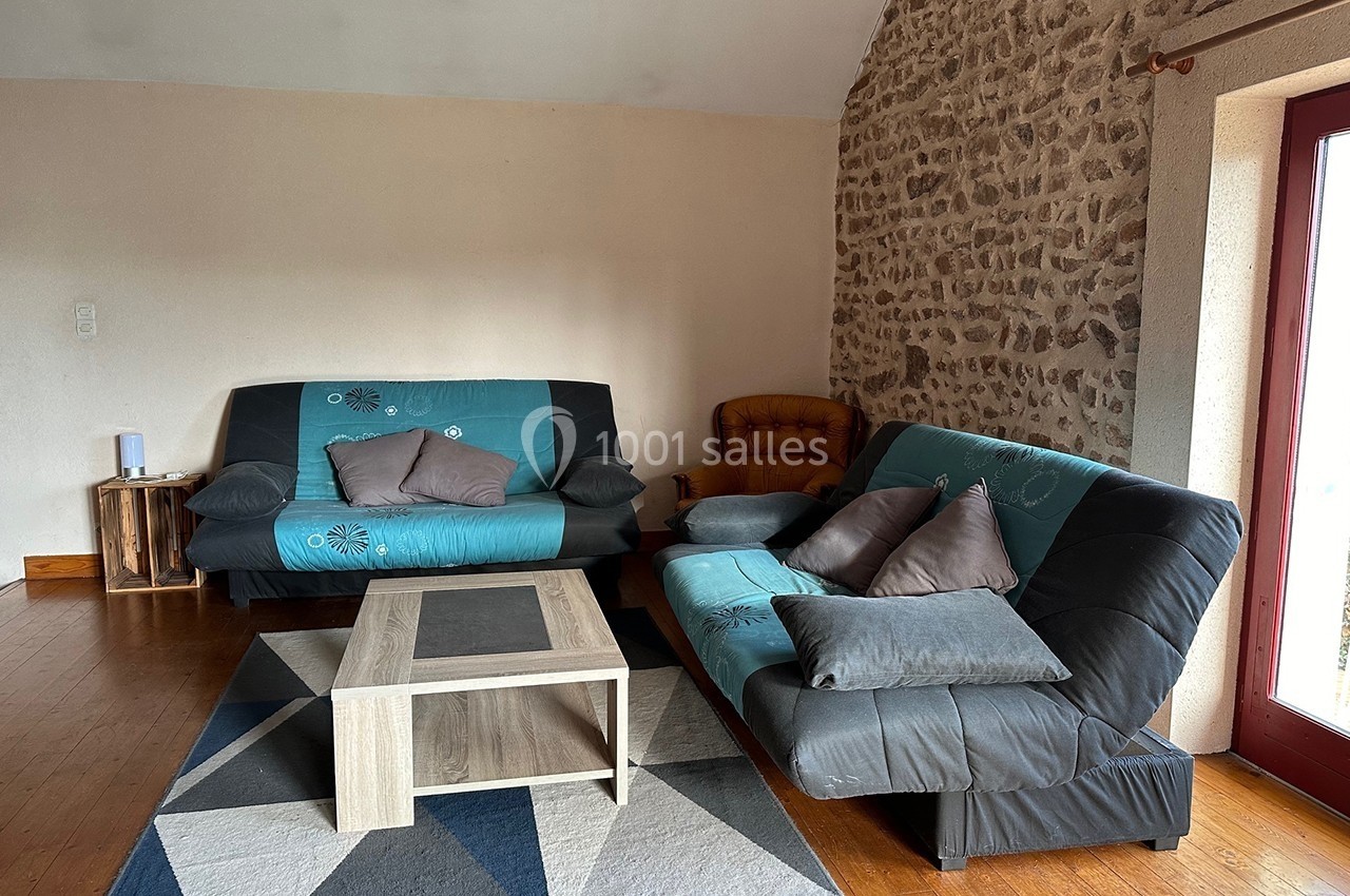 Deux canapés noirs et bleus avec coussins, une table basse en bois clair, sur un tapis géométrique dans un salon.