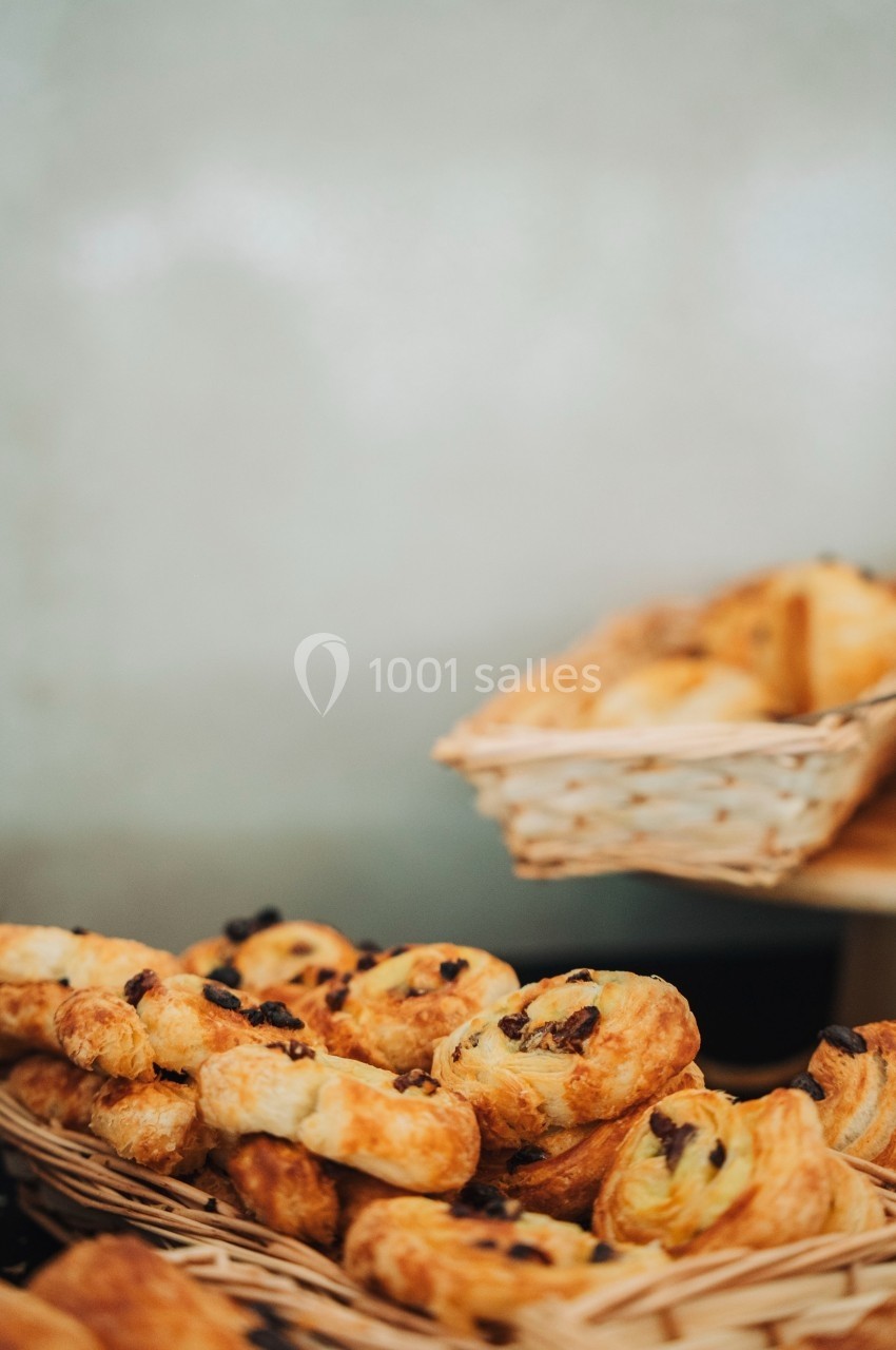 Viennoiseries dorées aux raisins disposées dans des paniers en osier sur un comptoir.