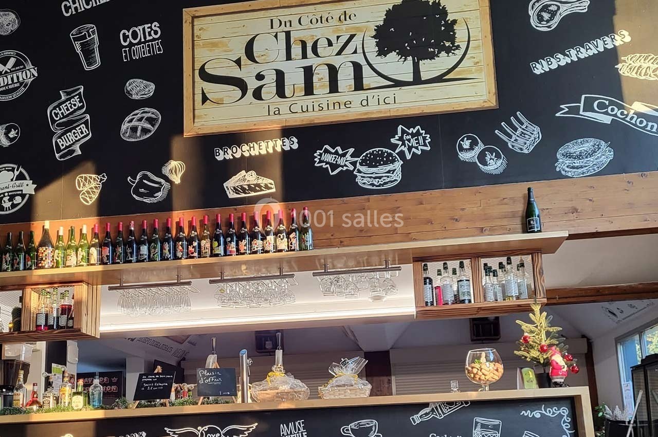 Intérieur d'un restaurant avec un comptoir, des bouteilles exposées et un mur décoré de dessins et inscriptions.