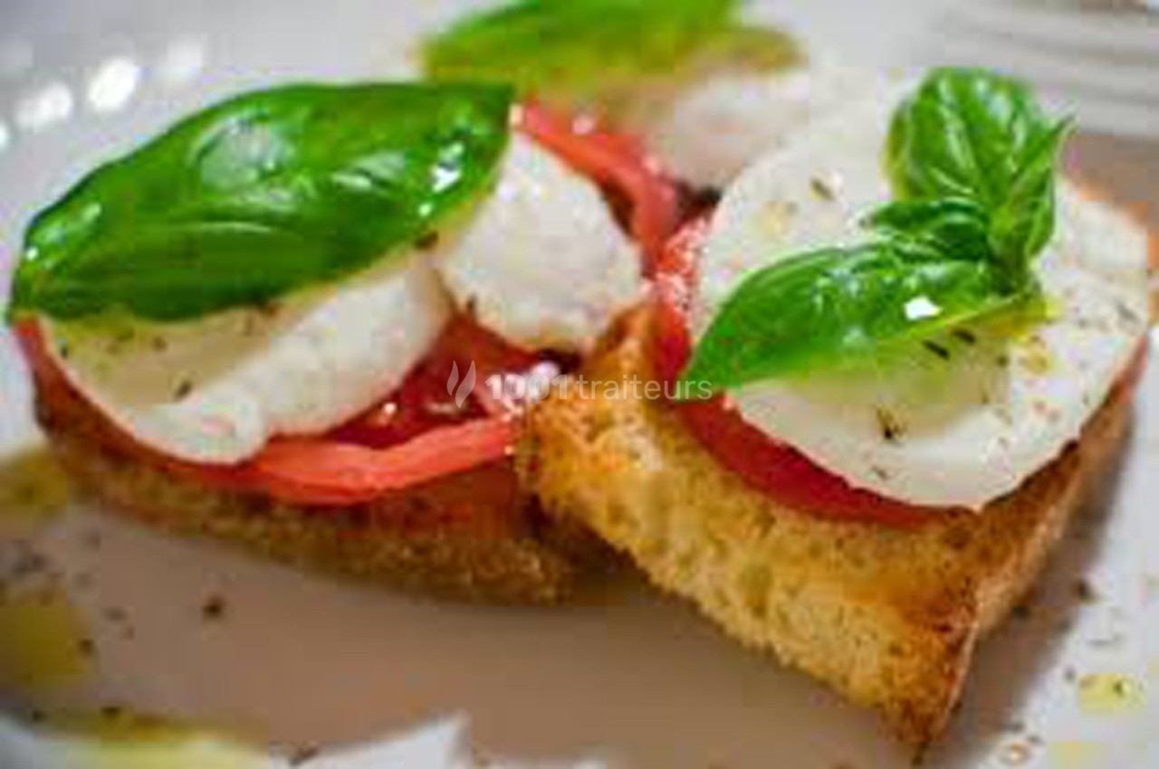 Tranches de pain grillé garnies de tomates, mozzarella, feuilles de basilic et filet d'huile d'olive.