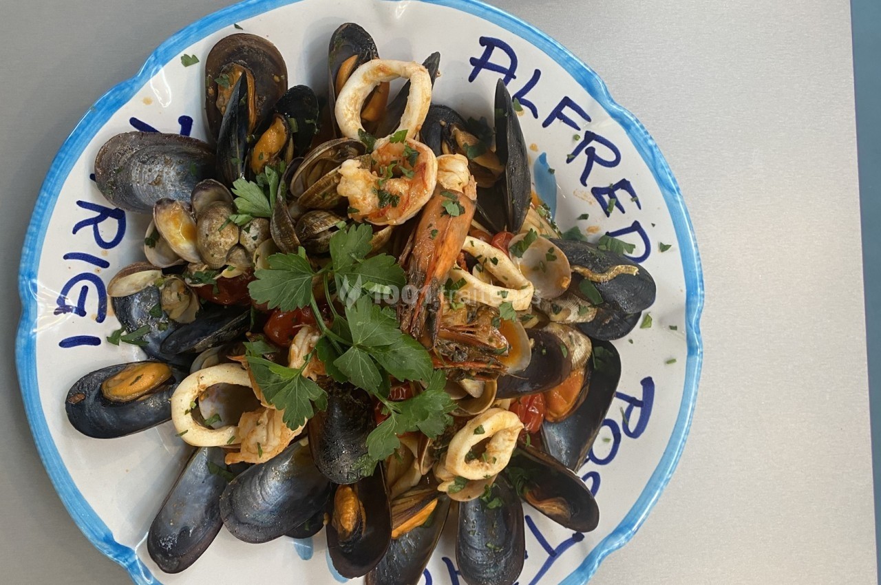 Assiette de fruits de mer variés avec moules, crevettes et calamars, garnie de persil frais.
