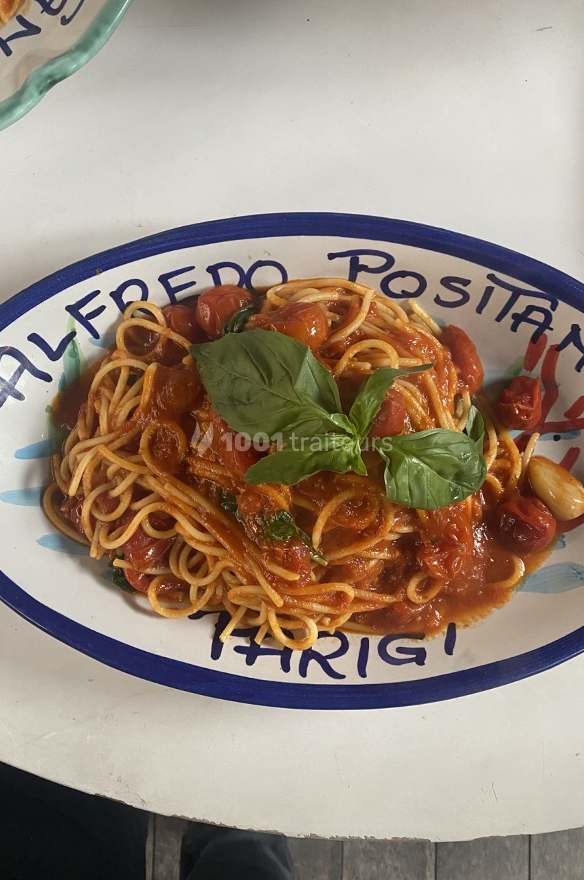 Assiette de spaghetti à la sauce tomate garnie de feuilles de basilic, servie dans un plat ovale décoré.