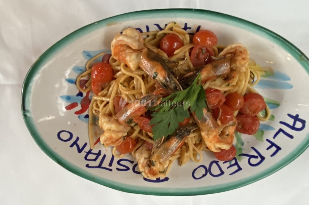 Assiette de linguine aux crevettes, tomates cerises et persil, servie sur une table avec une vaisselle décorative.