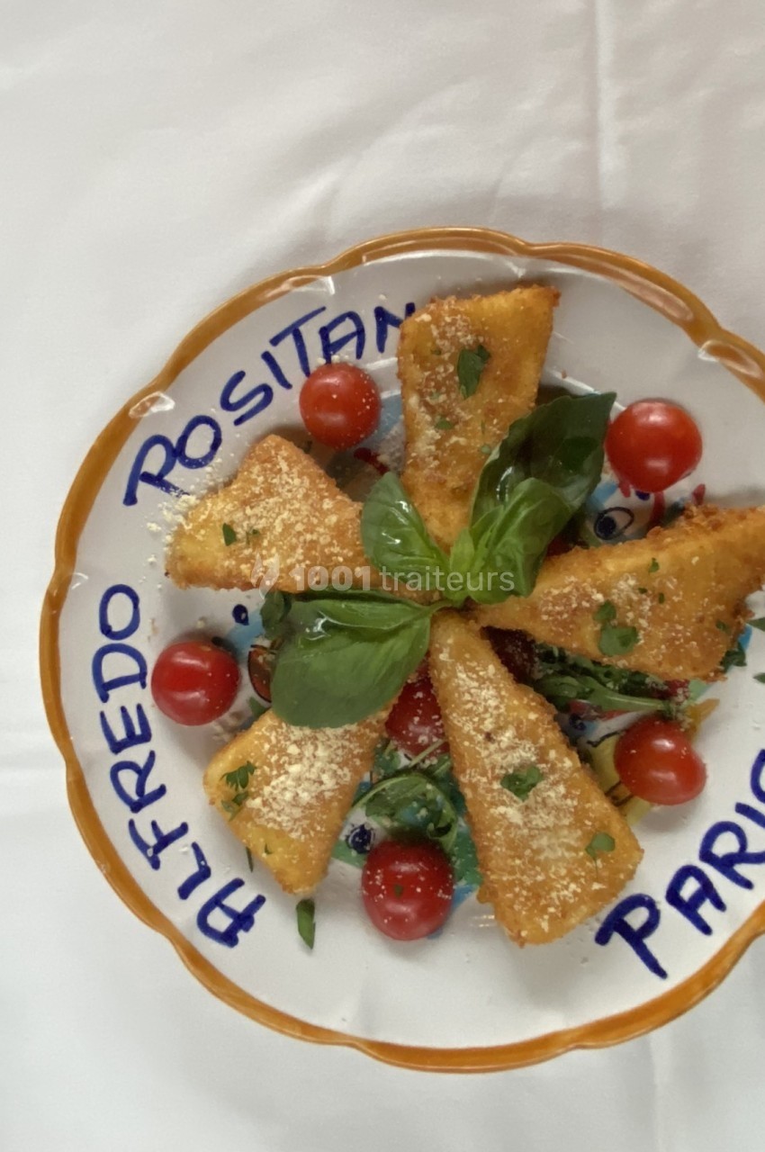 Assiette de croquettes dorées garnies de tomates cerises, basilic et parmesan, présentée sur une assiette décorée.