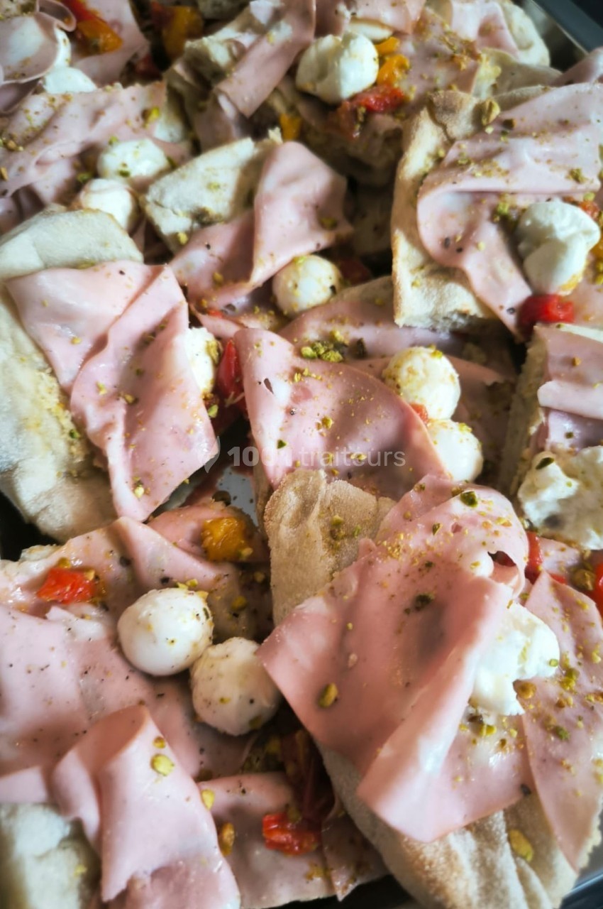 Tranches de focaccia garnies de mortadelle, mozzarella, poivrons grillés et éclats de pistache.