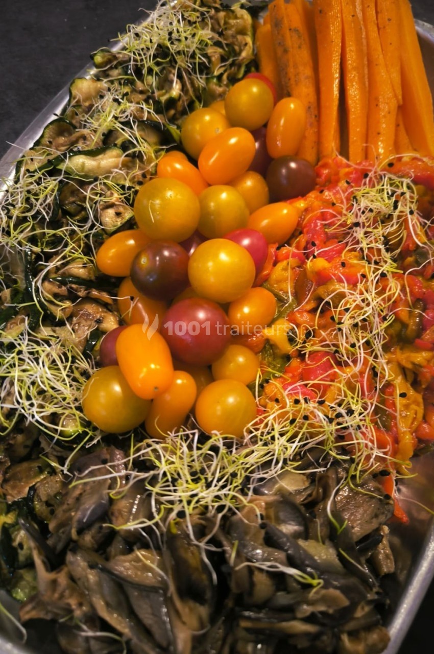 Plateau de légumes colorés comprenant tomates cerises, carottes, courgettes, poivrons, champignons et germes.