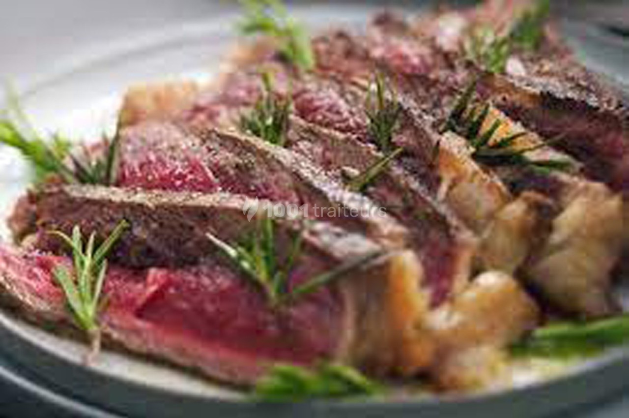 Tranches de steak saignant garnies de brins de romarin, servies sur une assiette.