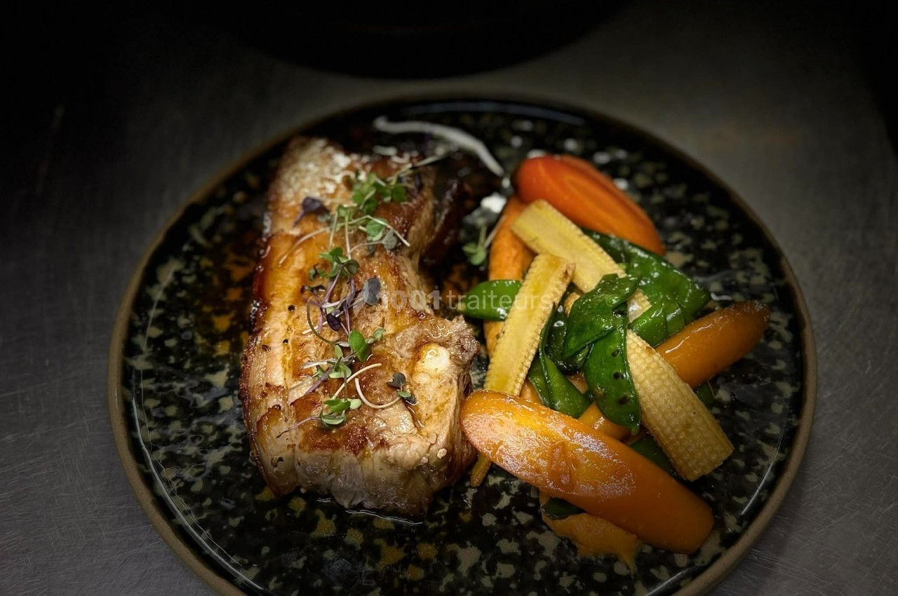 Plat de viande grillée accompagné de légumes sautés, dont carottes, mini-maïs et pois gourmands, servi sur une assiette…