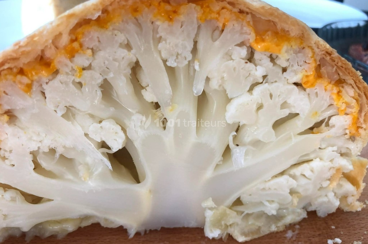 Chou-fleur en croûte dorée, coupé en deux, révélant sa texture intérieure et une garniture au fromage.