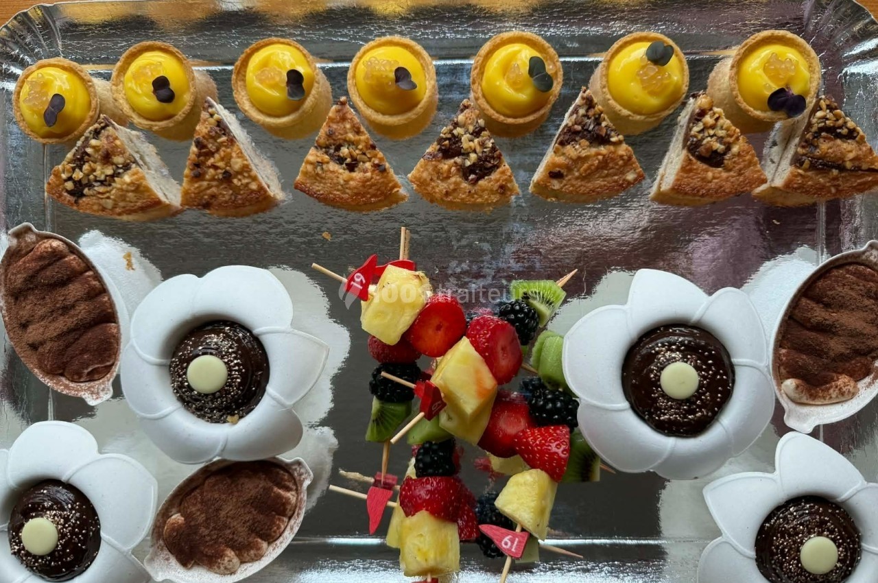 Plateau de desserts variés comprenant mignardises, brochettes de fruits, tartelettes et gâteaux décorés.