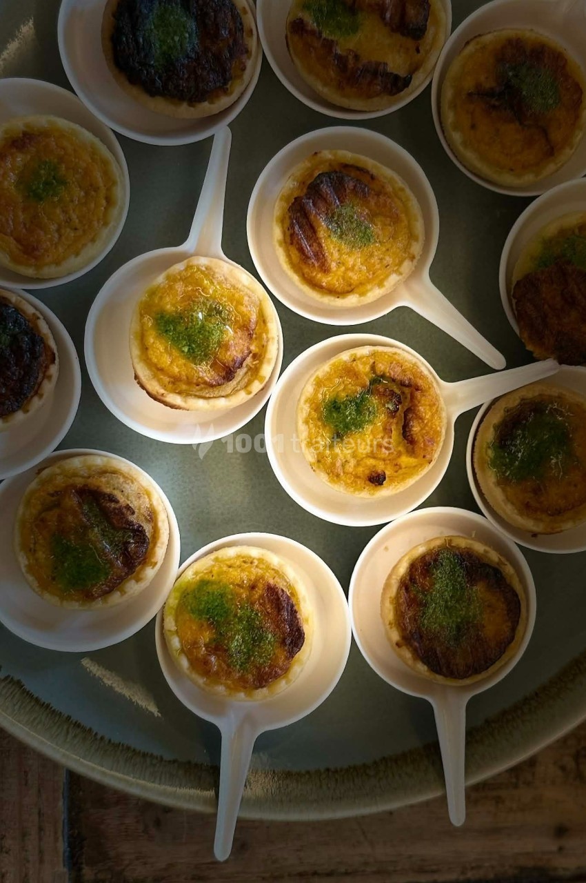 Petites portions de crème brûlée servies dans des cuillères blanches, garnies d'herbes fraîches.