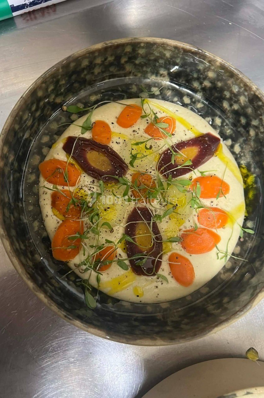 Bol contenant une purée crémeuse garnie de carottes, betteraves, herbes fraîches et filet d'huile d'olive.