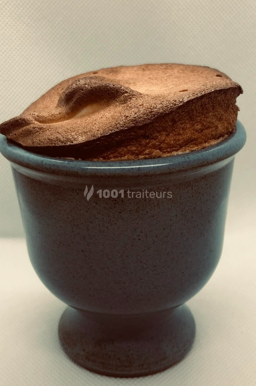 Soufflé doré et gonflé présenté dans un ramequin en céramique sur fond neutre.