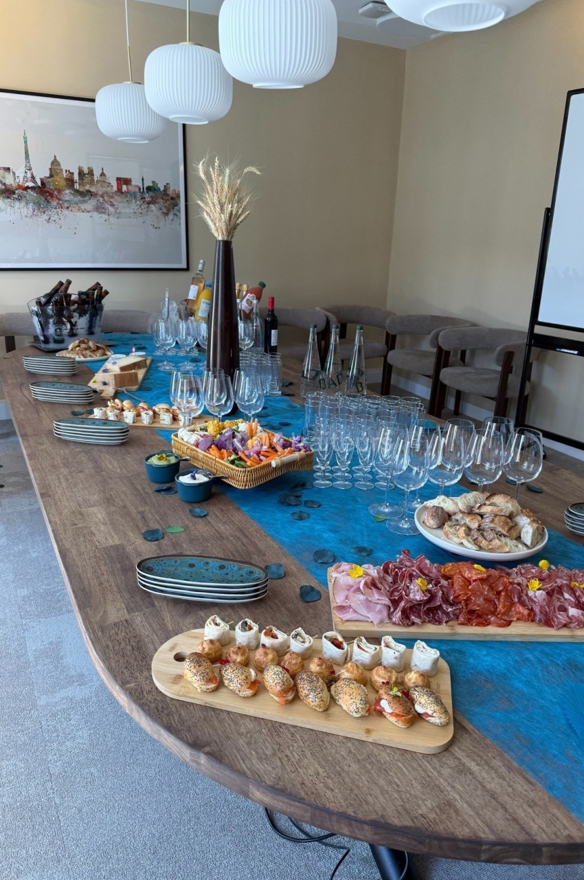 Table dressée avec un buffet de charcuterie, fromages, amuse-bouches, verres à vin et décorations élégantes.