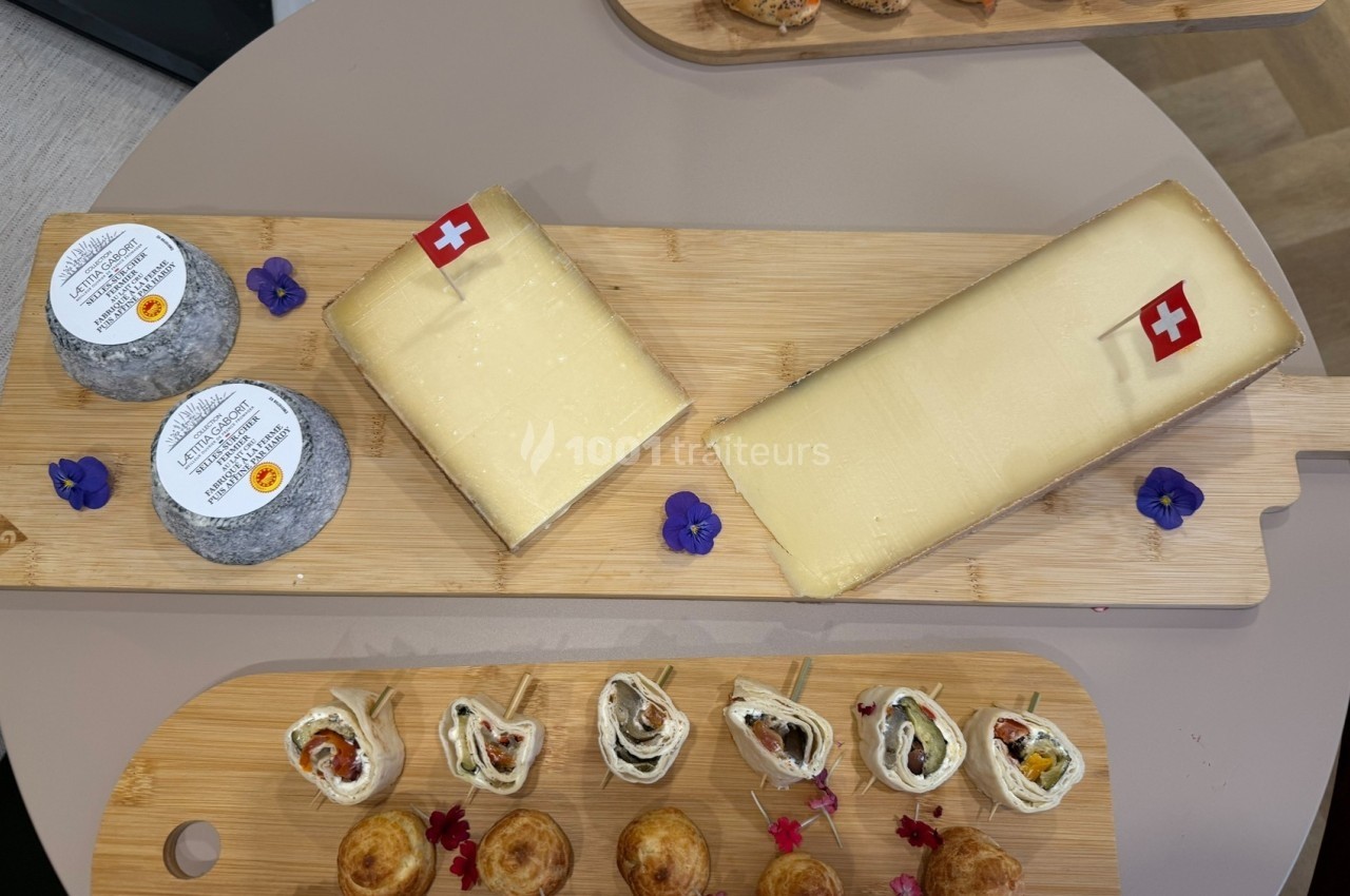 Plateaux en bois garnis de fromages suisses, de fleurs comestibles et d'amuse-bouches variés.