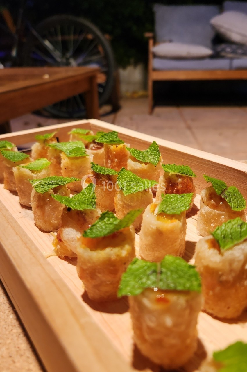 Bouchées croustillantes garnies de feuilles de menthe, présentées sur un plateau en bois dans un cadre extérieur.