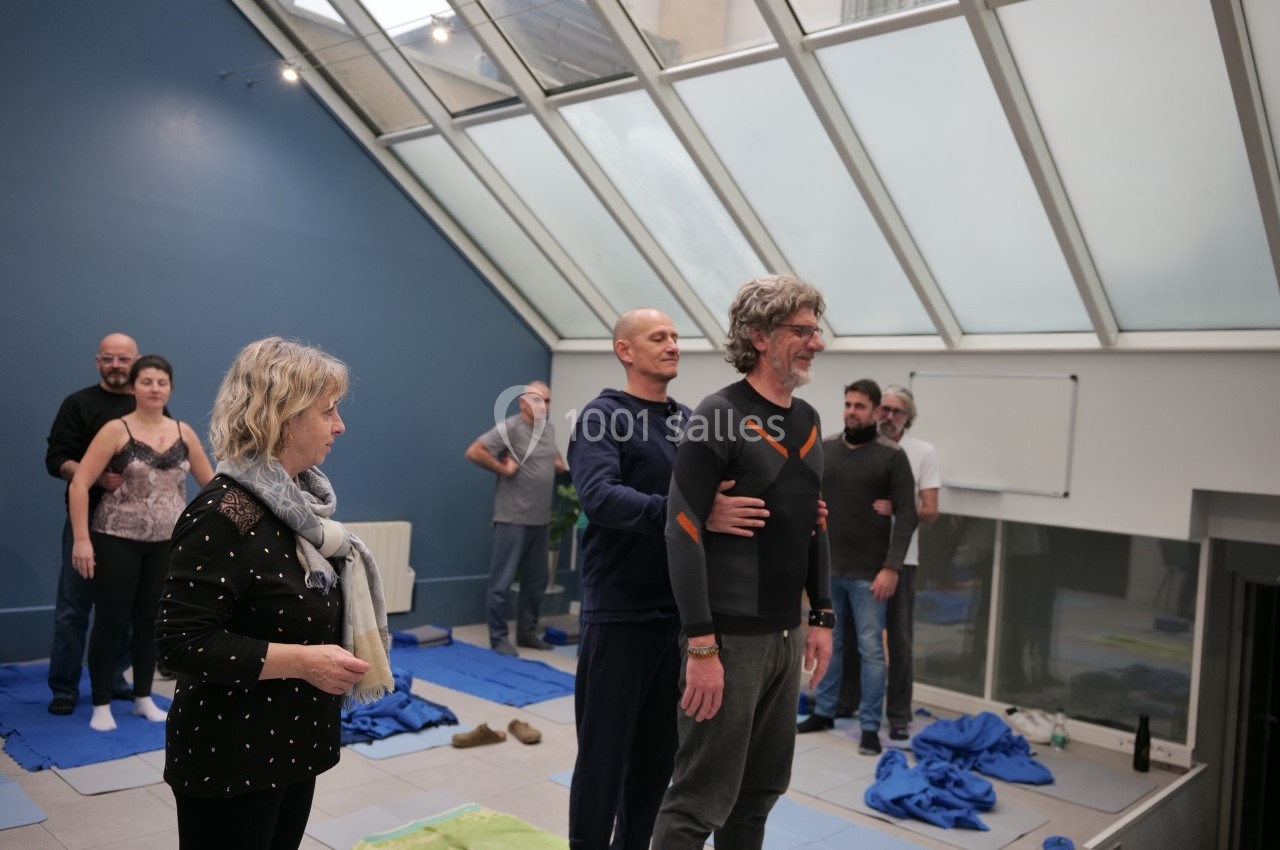 Des personnes participent à un atelier en groupe dans une salle lumineuse avec un toit vitré.