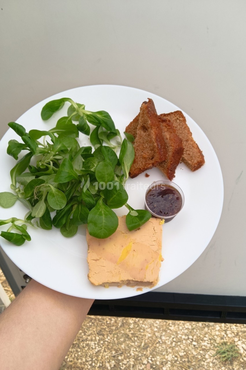 Assiette contenant du foie gras, de la mâche, des tranches de pain grillé et une petite portion de confiture.